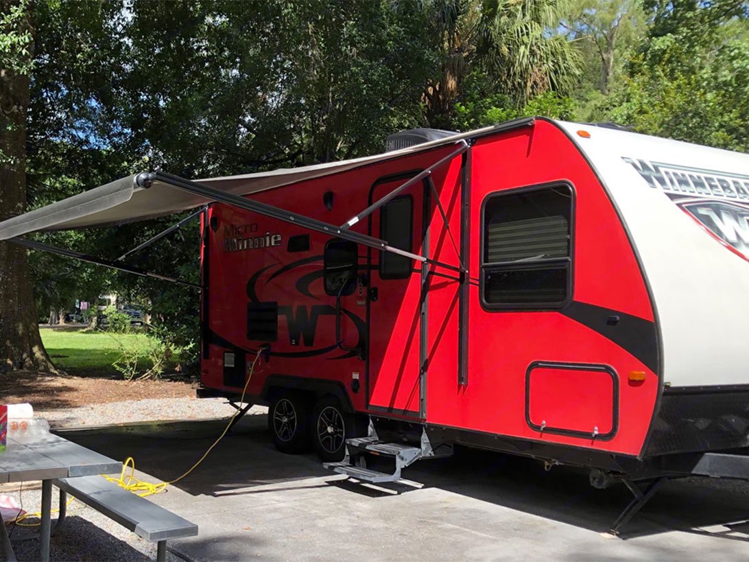 Exterior view of a red Winnebago camper with the awning open.