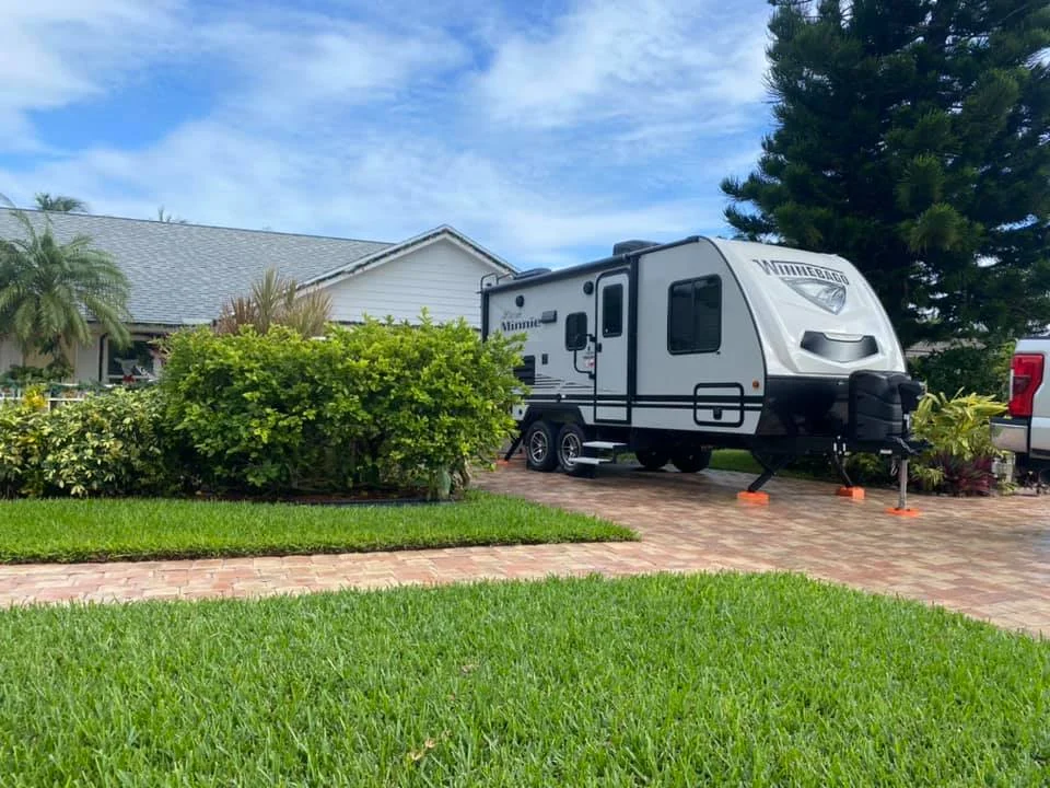Exterior view of a RV camper, parked in a driveway.