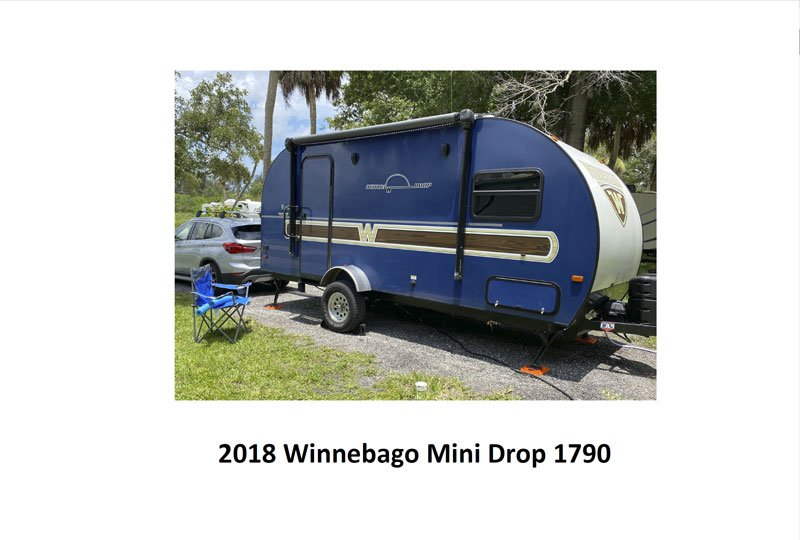 2018 Blue Micro Minnie parked outside in a driveway next to a blue outdoor chair.