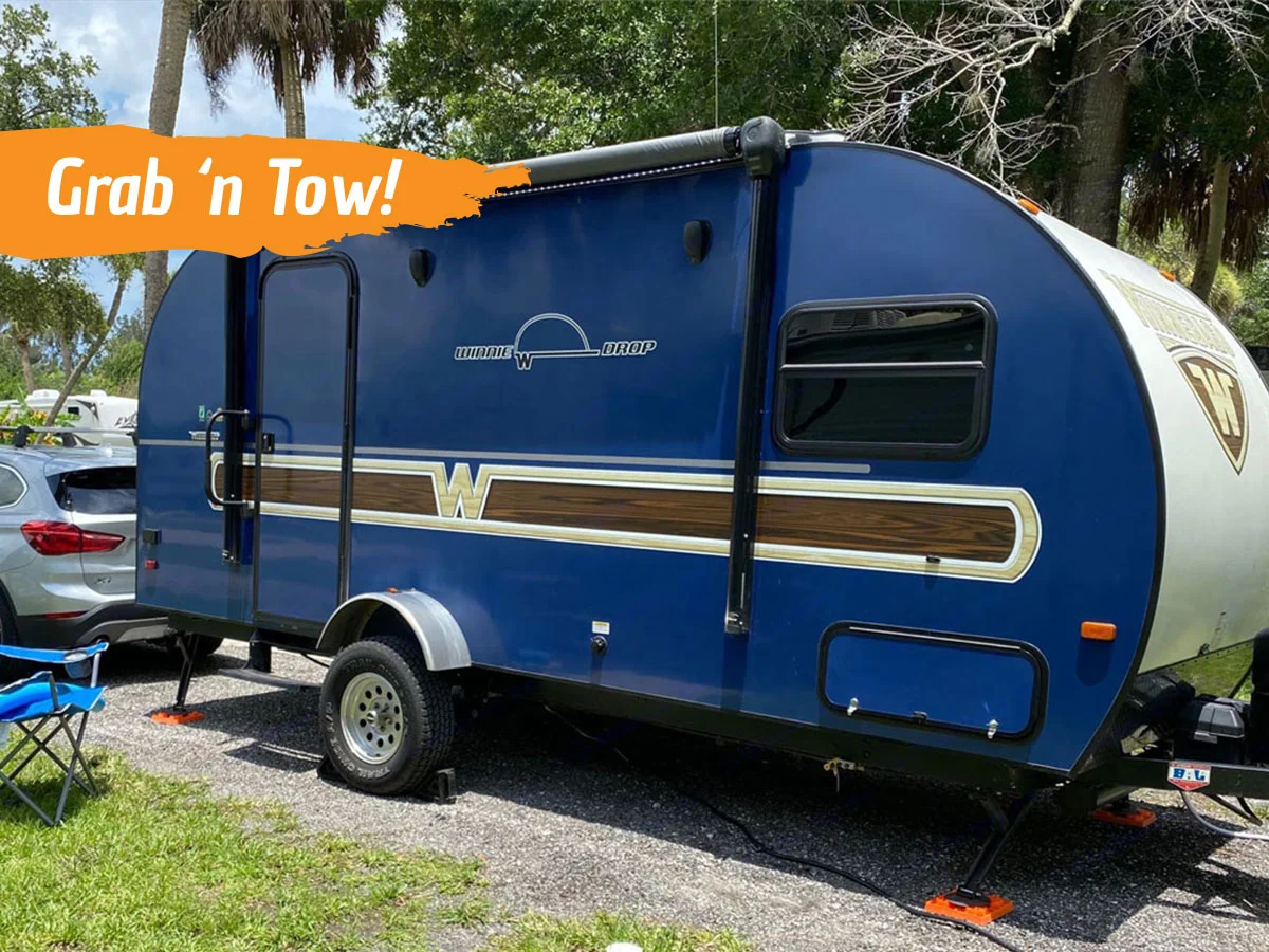 Dark blue towable Winnebago RV with a stripe down the side. Text reads "grab 'n tow!"