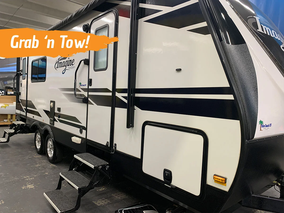 White towable rv with black stripes. text read "grab 'n tow"